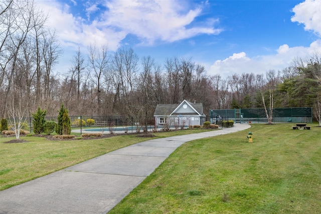view of property's community featuring a swimming pool, a yard, and fence