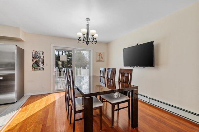 dining area featuring a baseboard heating unit, light wood-type flooring, a chandelier, and baseboards