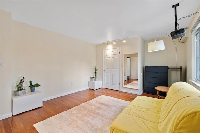 sitting room with rail lighting, baseboards, and wood finished floors