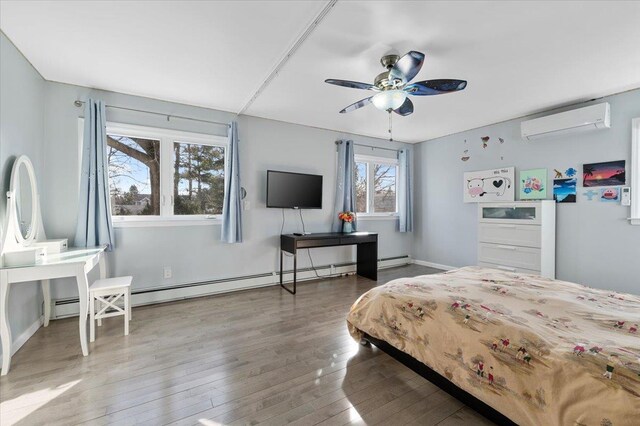 bedroom featuring a wall unit AC, baseboards, a baseboard heating unit, and hardwood / wood-style floors