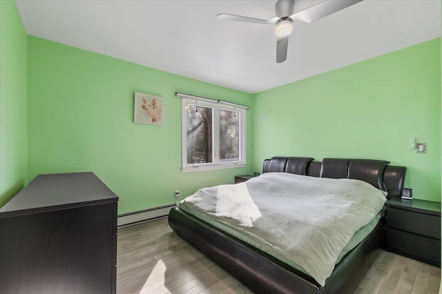 bedroom with a baseboard radiator, ceiling fan, and wood finished floors