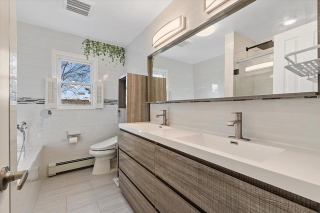 bathroom with tile walls, a baseboard radiator, visible vents, toilet, and a sink