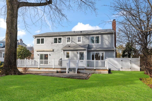 back of house with fence, a lawn, a wooden deck, a gate, and a chimney