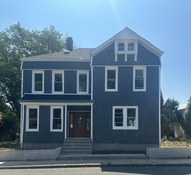 view of front of home with entry steps and a chimney