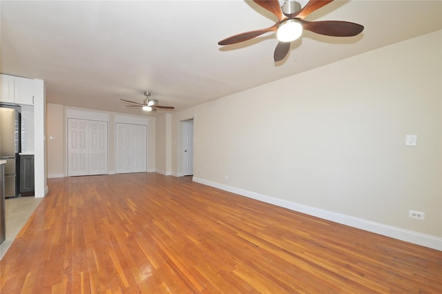 unfurnished living room with light wood-type flooring, ceiling fan, and baseboards