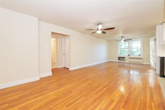 unfurnished living room with baseboards, a fireplace, light wood-style flooring, and radiator heating unit