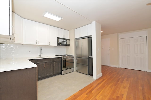 kitchen with decorative backsplash, stainless steel appliances, light countertops, white cabinetry, and a sink