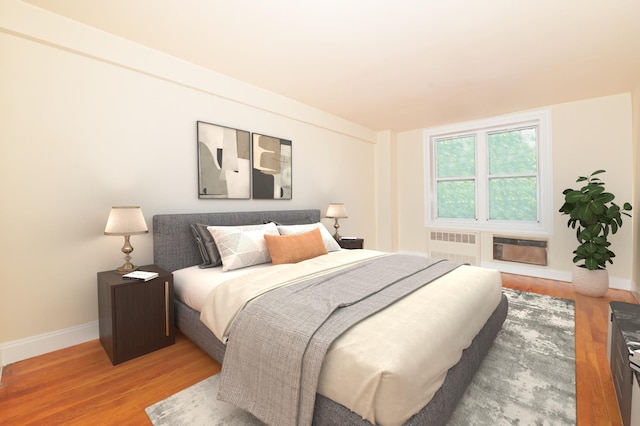 bedroom with light wood-style floors, radiator, a wall mounted air conditioner, and baseboards