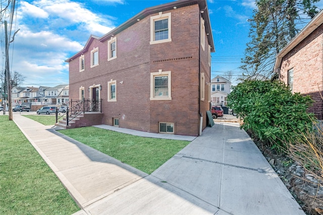 view of home's exterior with brick siding, a lawn, and a residential view