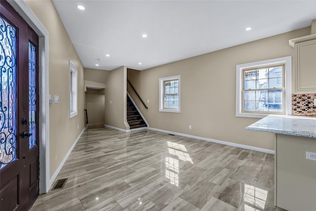 foyer entrance featuring baseboards, stairway, and a healthy amount of sunlight