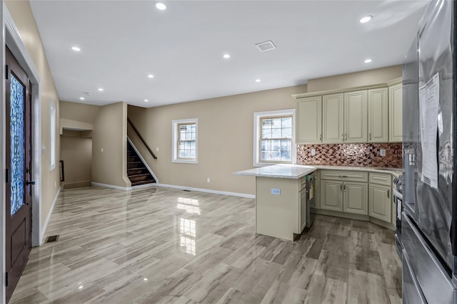 kitchen with visible vents, baseboards, cream cabinetry, tasteful backsplash, and stainless steel fridge