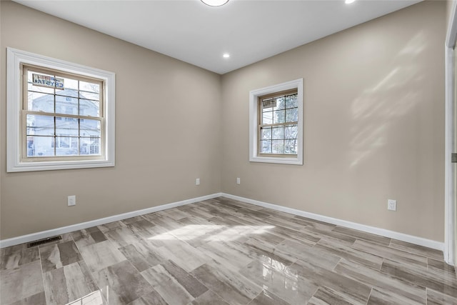 empty room featuring light wood-style floors, visible vents, baseboards, and recessed lighting