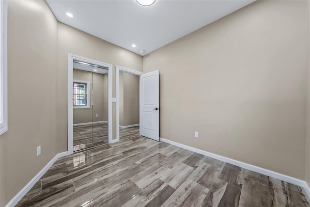 unfurnished bedroom with a closet, recessed lighting, wood finished floors, and baseboards