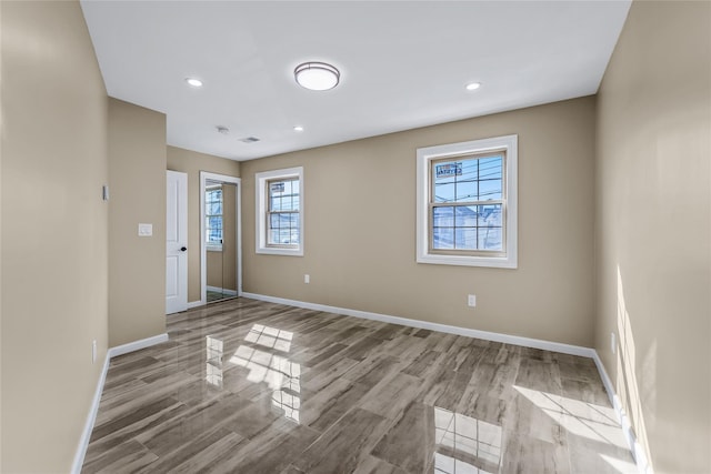 unfurnished room with baseboards, recessed lighting, wood finished floors, and a healthy amount of sunlight