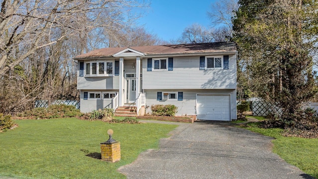 raised ranch featuring driveway, an attached garage, and a front lawn