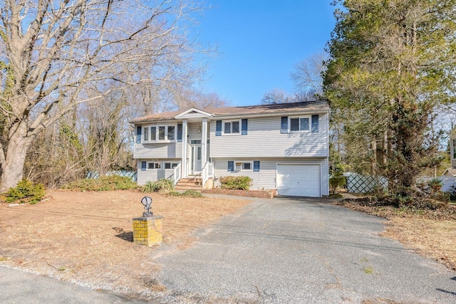 split foyer home featuring a garage and aphalt driveway