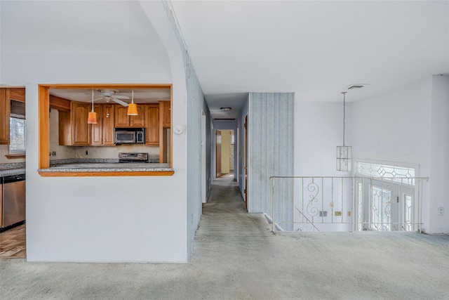 kitchen featuring carpet floors, hanging light fixtures, decorative backsplash, appliances with stainless steel finishes, and brown cabinetry