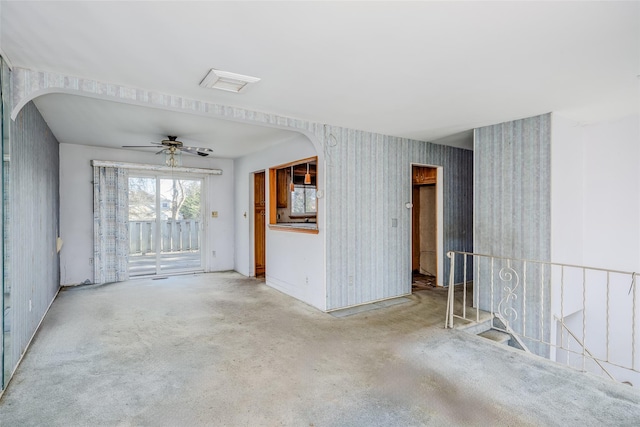 empty room featuring wallpapered walls, visible vents, arched walkways, and carpet flooring