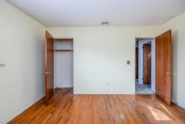 unfurnished bedroom with a closet, visible vents, and light wood-style floors