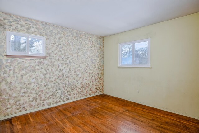 spare room featuring hardwood / wood-style floors, plenty of natural light, and baseboards