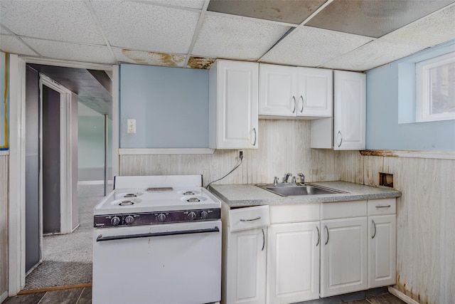 kitchen with white range with electric cooktop, wainscoting, a sink, and white cabinetry