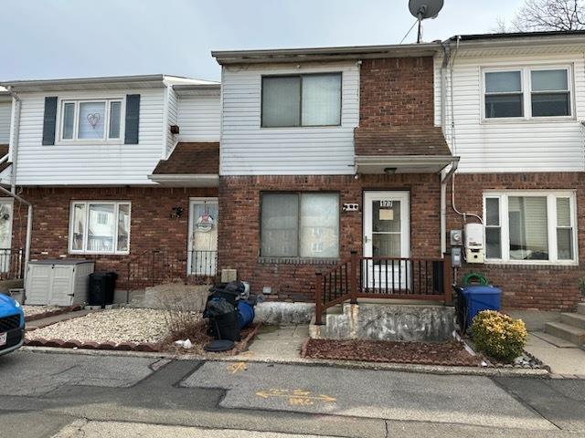 townhome / multi-family property featuring central AC, brick siding, and roof with shingles