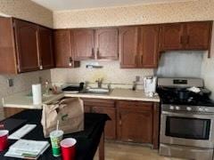 kitchen with light countertops, gas stove, and a sink