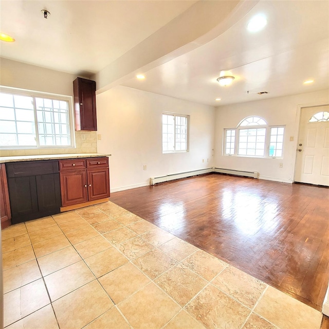 kitchen with a baseboard heating unit, light countertops, backsplash, and a healthy amount of sunlight