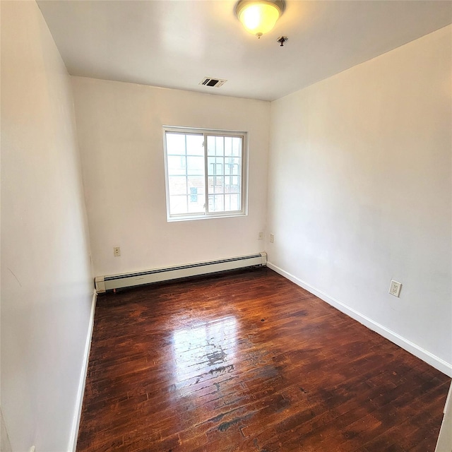 empty room featuring a baseboard heating unit, baseboards, visible vents, and hardwood / wood-style floors