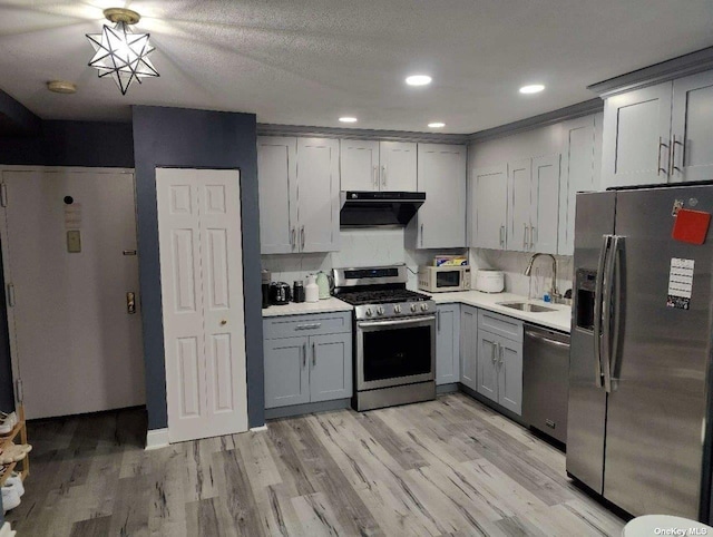 kitchen featuring light countertops, gray cabinetry, appliances with stainless steel finishes, a sink, and under cabinet range hood