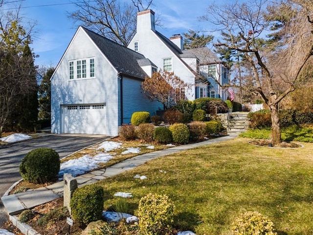 view of property exterior featuring aphalt driveway, a lawn, a garage, and a chimney