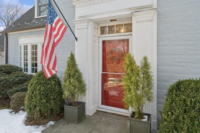 entrance to property featuring roof with shingles