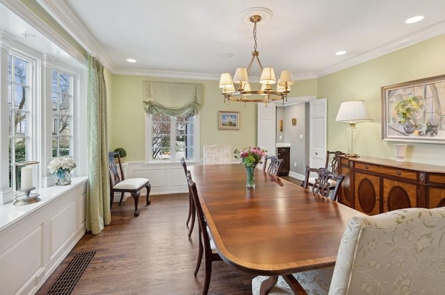 dining room with crown molding, dark wood-type flooring, recessed lighting, a notable chandelier, and a decorative wall