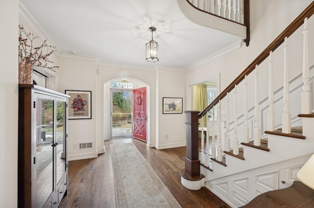 entrance foyer featuring visible vents, dark wood-style floors, arched walkways, crown molding, and baseboards