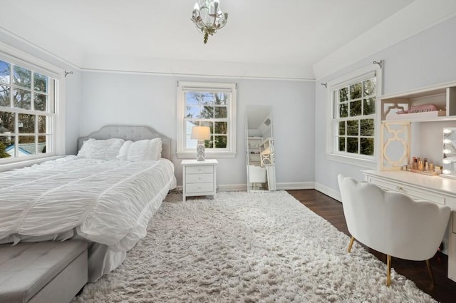 bedroom with multiple windows, wood finished floors, and baseboards