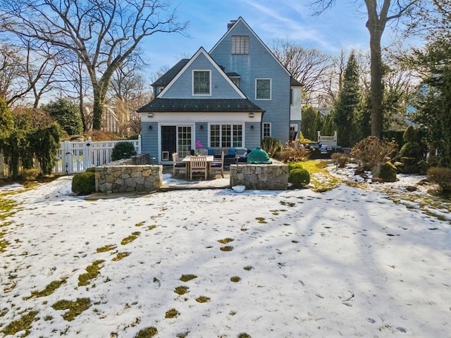 snow covered back of property featuring a patio area, outdoor lounge area, and fence