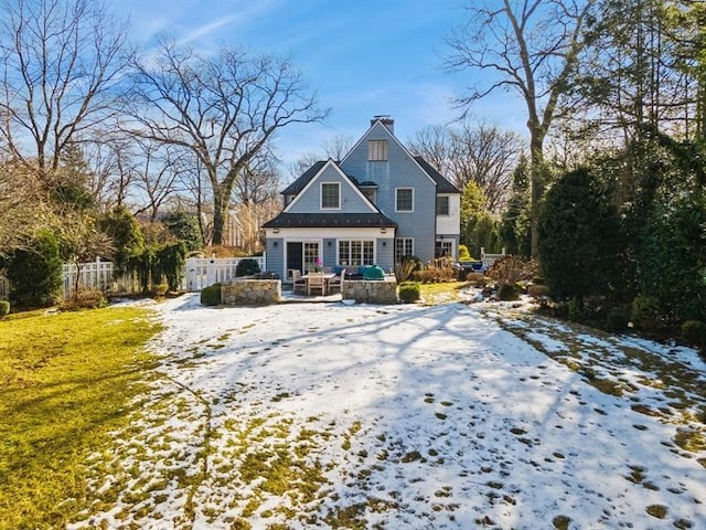 snow covered property with a chimney and fence