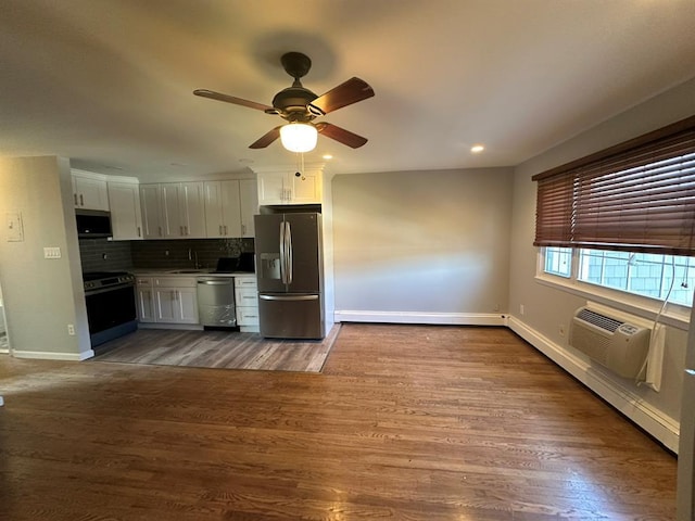 kitchen with wood finished floors, white cabinetry, appliances with stainless steel finishes, decorative backsplash, and a wall mounted air conditioner