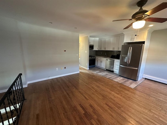 kitchen featuring baseboards, appliances with stainless steel finishes, wood finished floors, white cabinetry, and backsplash