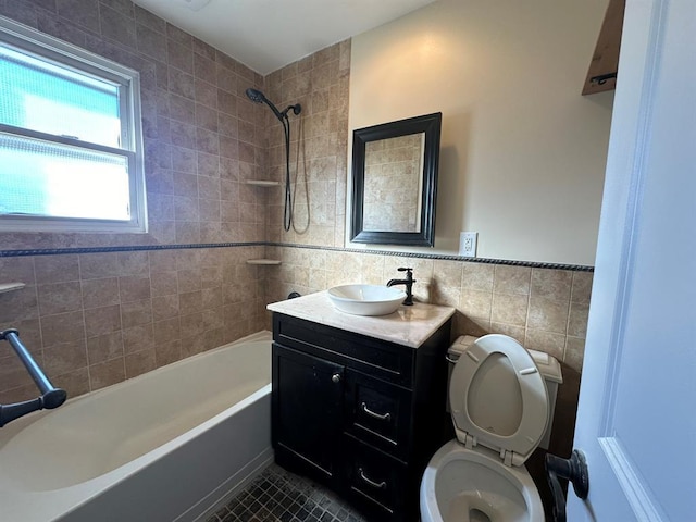 bathroom with tile walls, toilet, vanity,  shower combination, and tile patterned floors