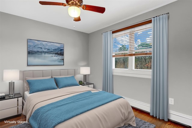 bedroom featuring a baseboard heating unit, ceiling fan, wood finished floors, and baseboards