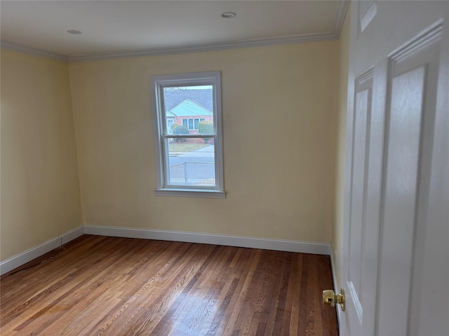 empty room with ornamental molding, hardwood / wood-style floors, and baseboards