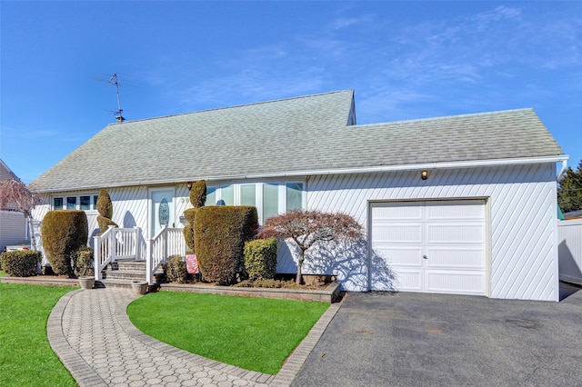 ranch-style house with a front lawn, a shingled roof, an attached garage, and aphalt driveway