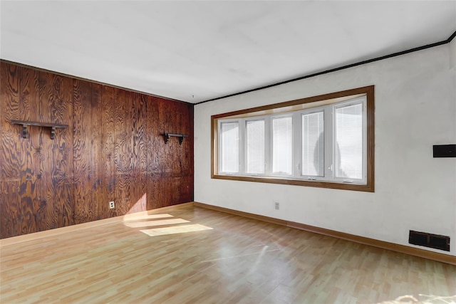 unfurnished room featuring wood finished floors, visible vents, and baseboards