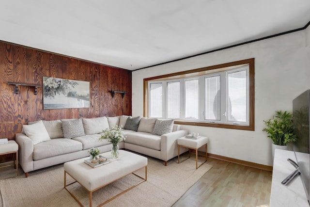 living area featuring light wood-style floors, wooden walls, and baseboards