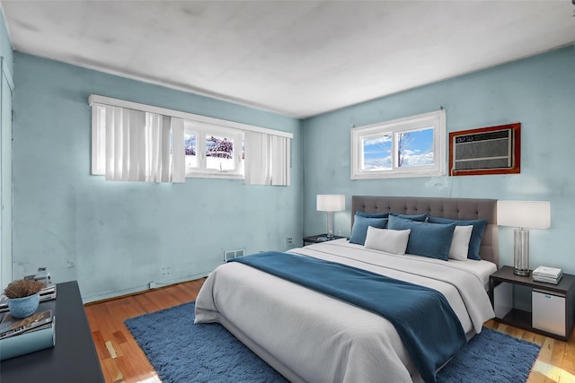 bedroom featuring visible vents, wood finished floors, and a wall mounted air conditioner