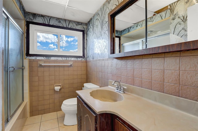 full bath with wallpapered walls, toilet, tile patterned floors, vanity, and tile walls