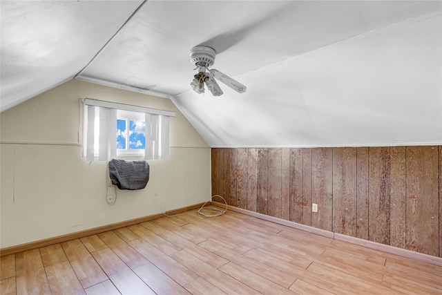 bonus room featuring ceiling fan, vaulted ceiling, wooden walls, wood finished floors, and baseboards