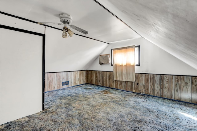 additional living space with wainscoting, a wall mounted air conditioner, vaulted ceiling, carpet flooring, and wood walls