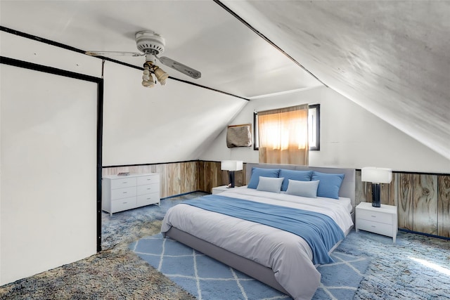 carpeted bedroom with lofted ceiling, wood walls, and a wainscoted wall